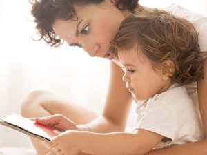 Woman and baby girl reading on bed